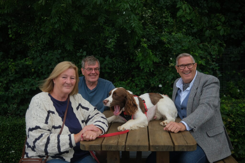 Graeme Hall with two other people and a white and brown dog